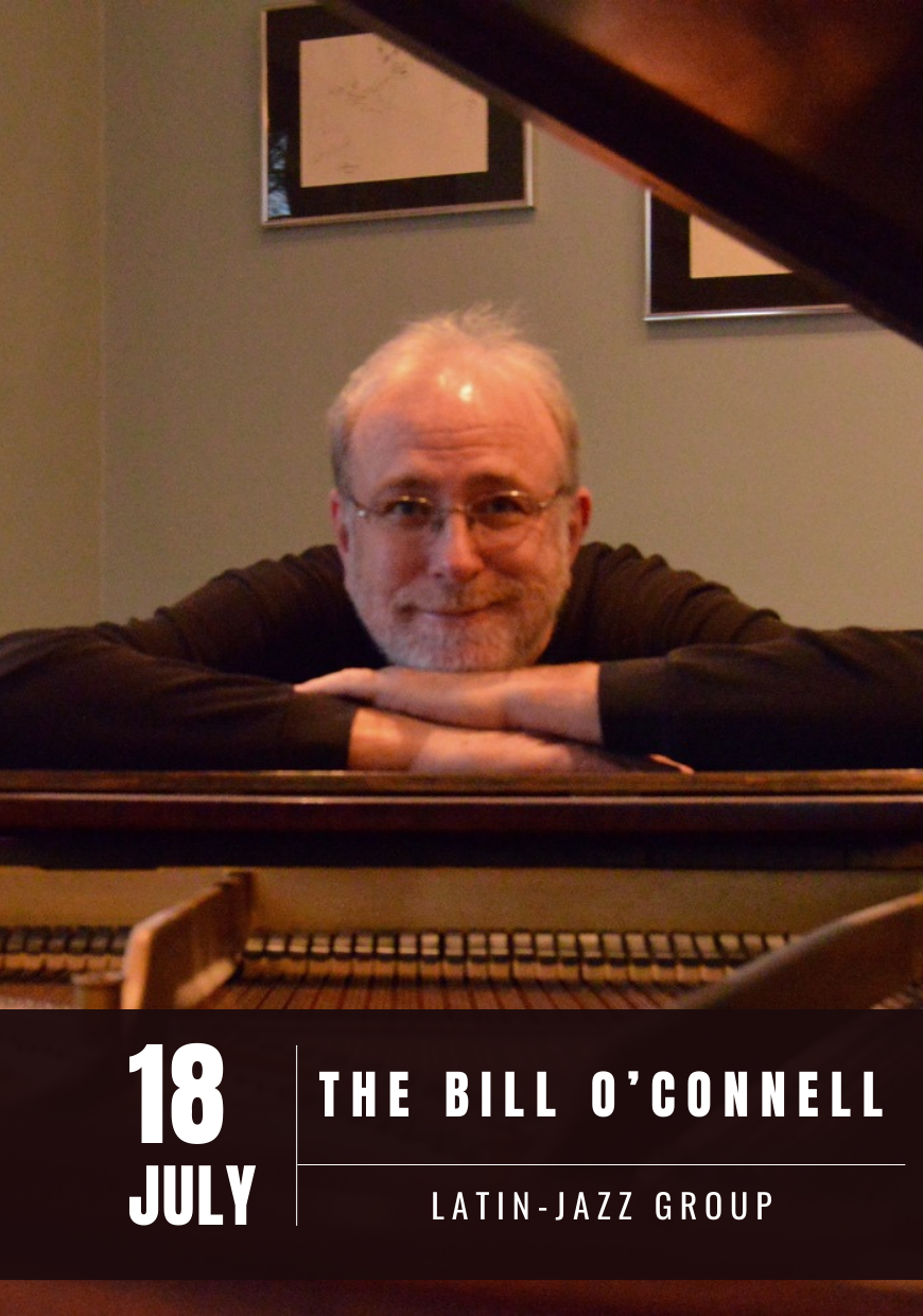 Bill O'Connell leaning on a piano
