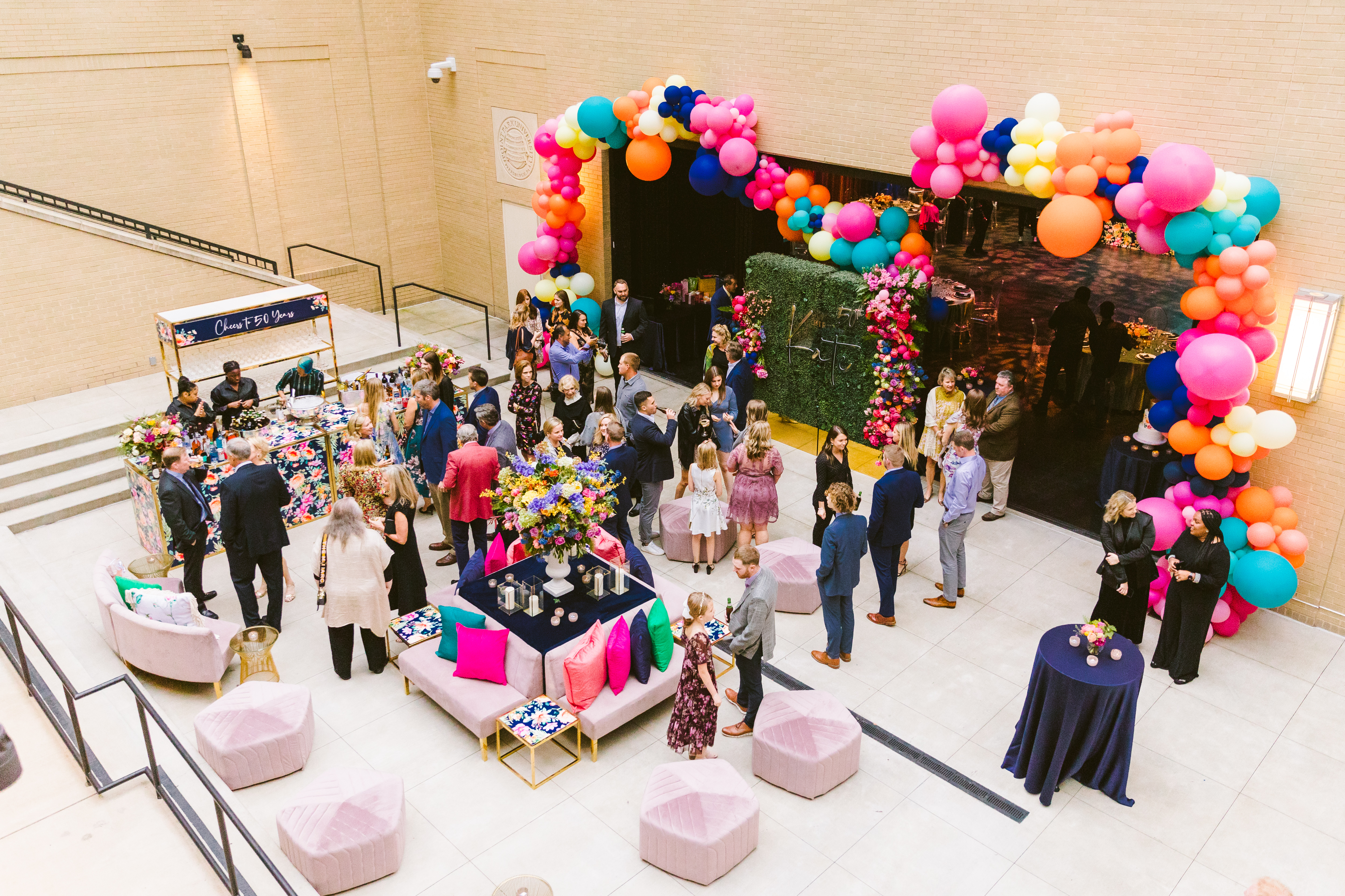 people chatting under a balloon arch